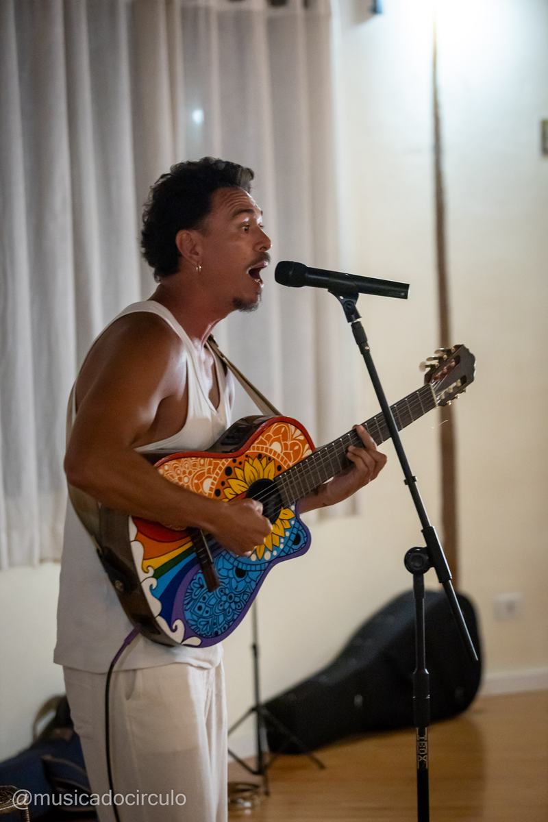 Diôgo tocando violão pintado num show intimista